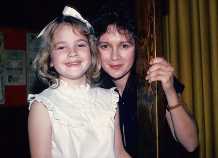drew in a white frock standing close with her mother 